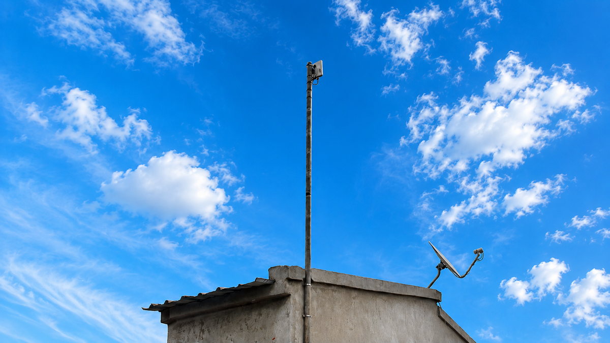 Antena exterior HETUALINK montada num mastro, recortada contra o céu